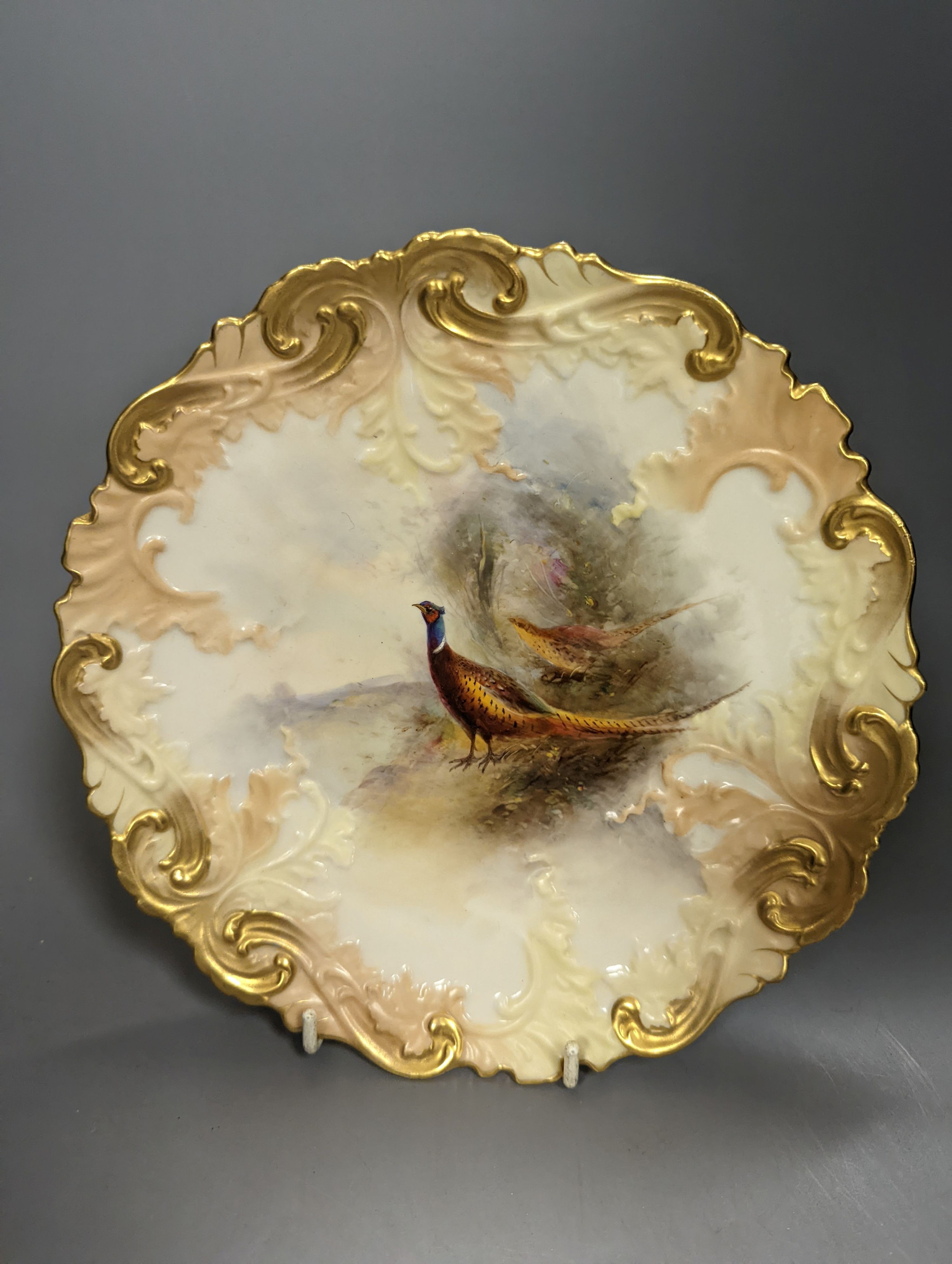 A Royal Worcester moulded plate painted with a brace of pheasants by James Stinton, not signed, date mark 1909 and a Royal Worcester fine plate painted with swimming fish, titled Char, by Harry Aryton, signed date mark f